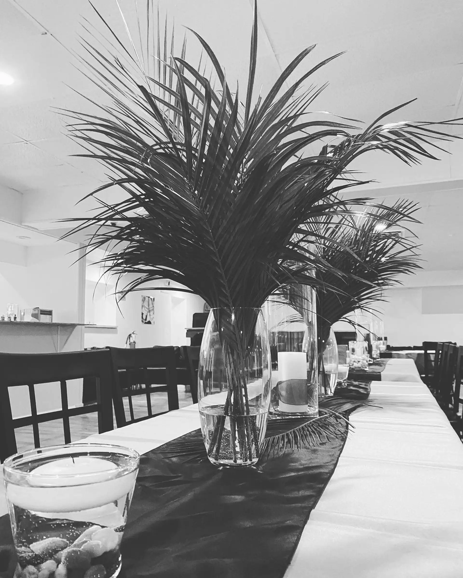 Reception tables dressed with palm centerpieces in the banquet hall