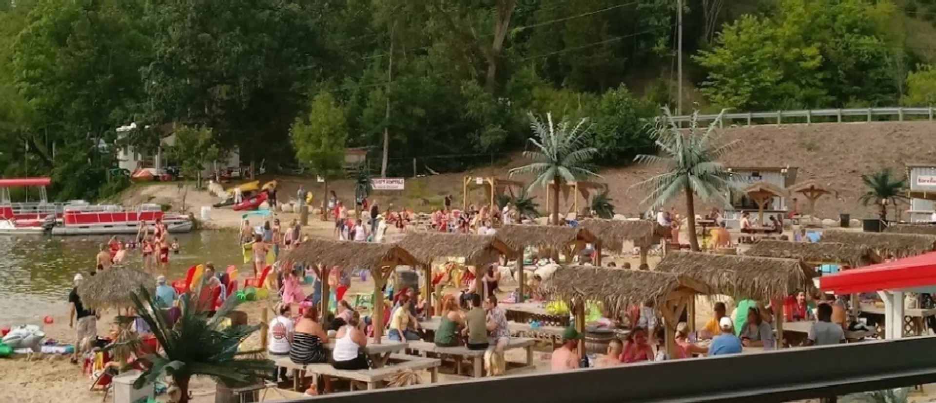 Summer crowd among the thatched tiki huts on the sand at Tiki Beach Resort