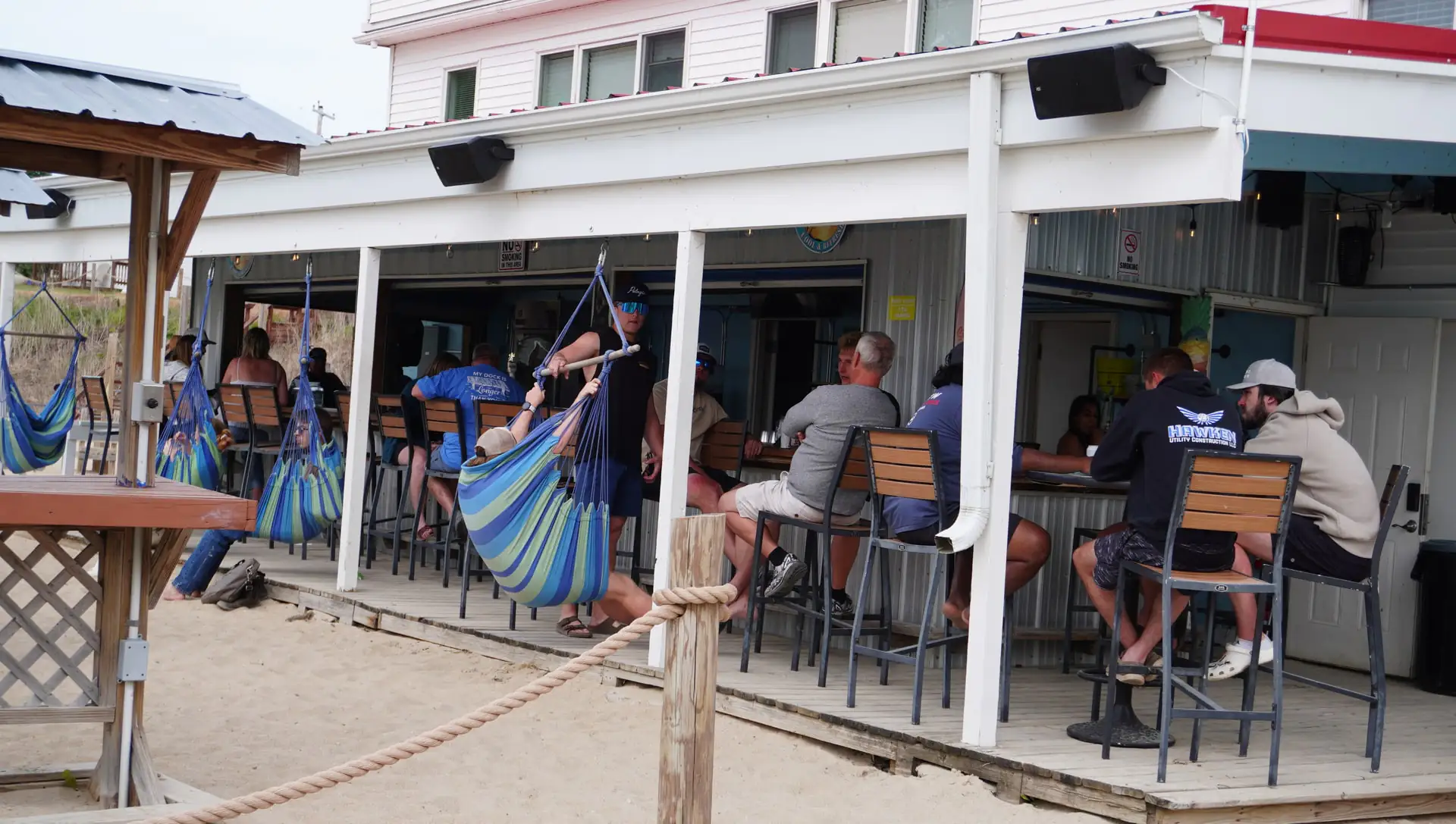 The beachside bar with hanging swing seats and guests on the deck