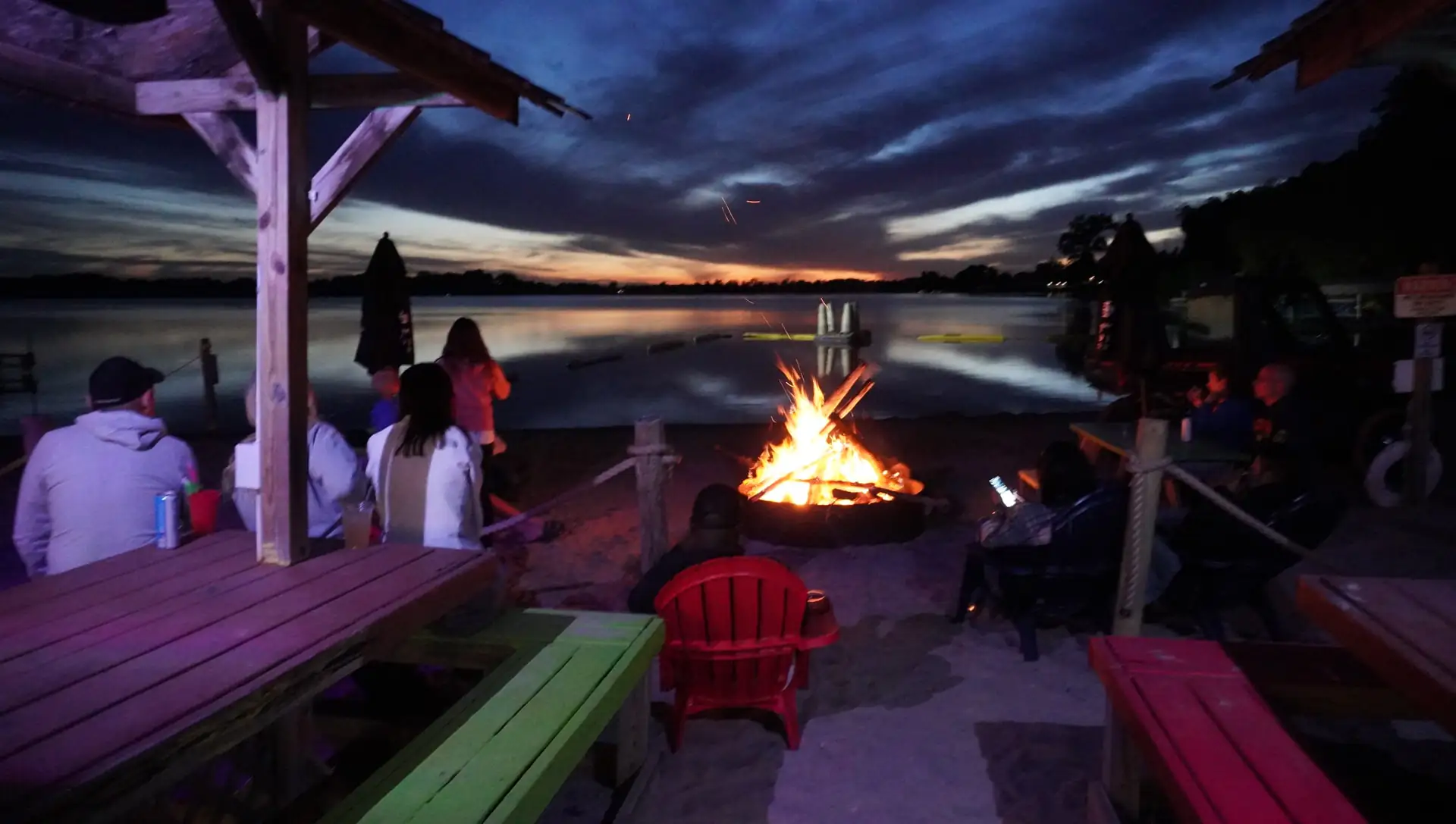 Guests gathered around the beach bonfire at twilight