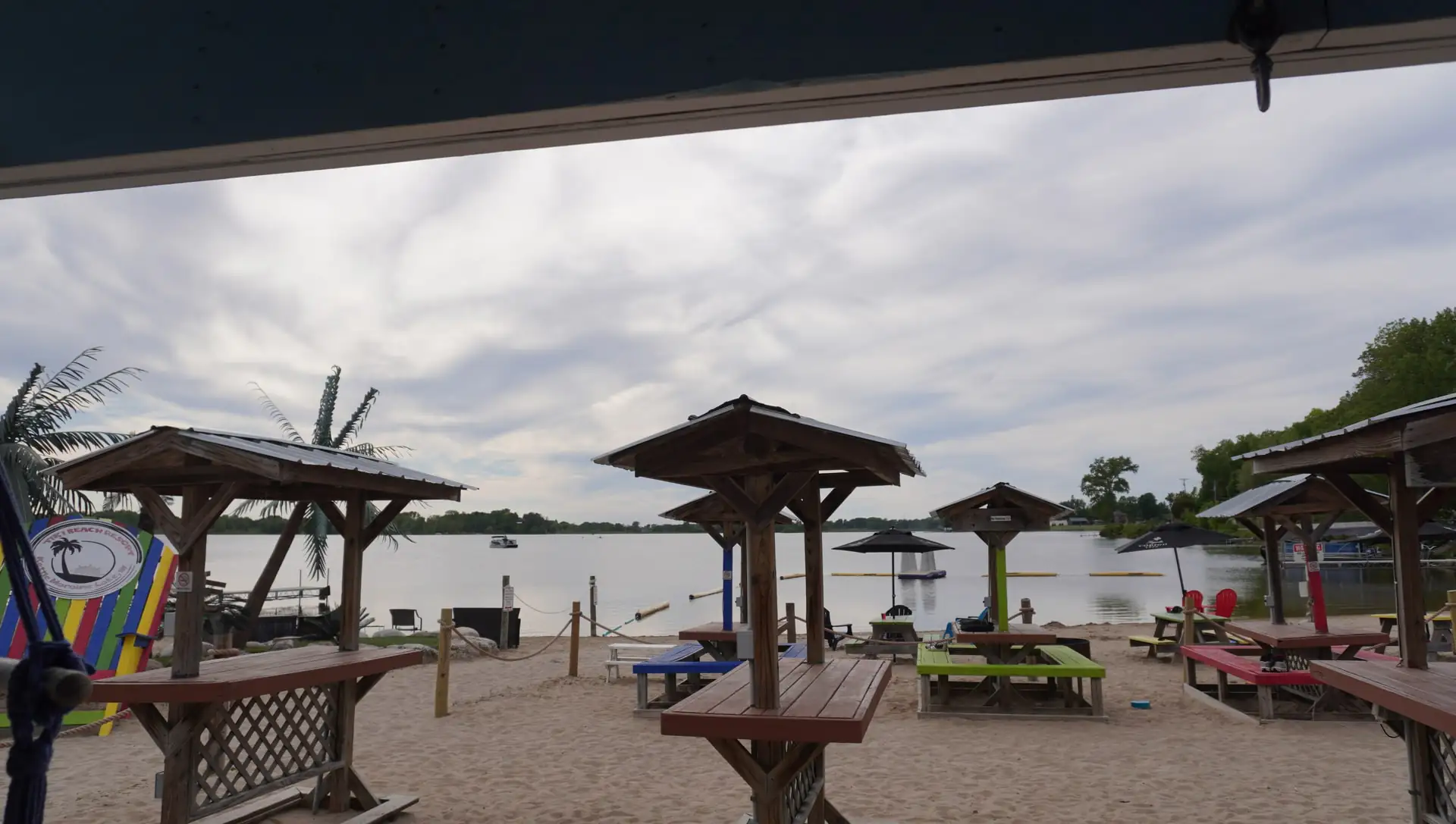 Thatched umbrellas and picnic tables on the sand at dusk