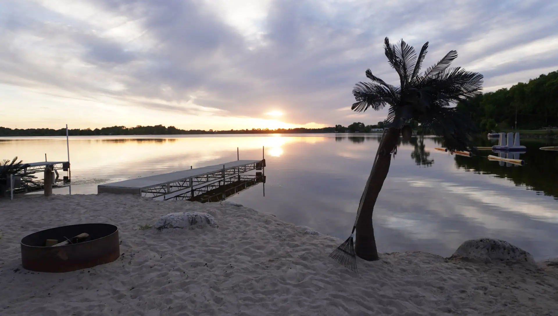 Sunset over the beach with the palm and fire pit by the water
